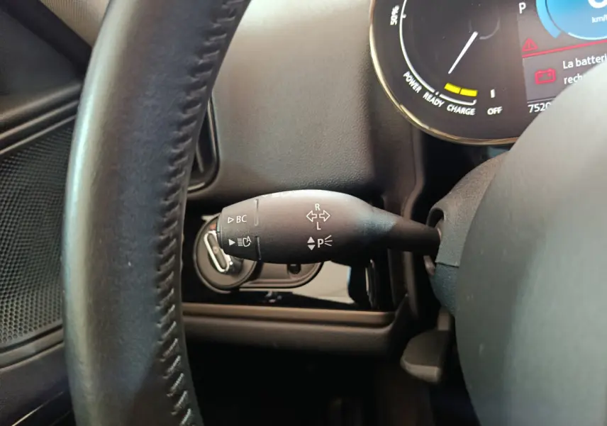 Gros plan sur la manette de clignotants côté gauche du volant noir dans l'habitacle d'une MINI Countryman blanche hybride rechargeable.