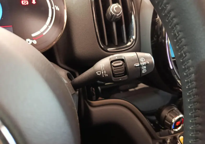 Gros plan sur la commande d’essuie-glace à gauche du volant cuir dans l’habitacle noir du MINI Countryman blanc.
