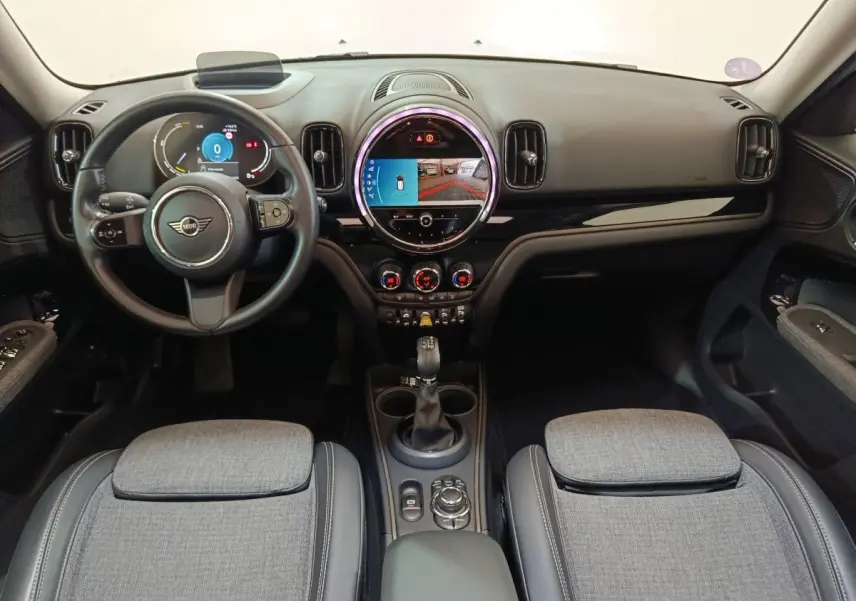 Intérieur du MINI Countryman Cooper SE blanc, vue frontale du tableau de bord avec écran tactile rond et volant cuir.