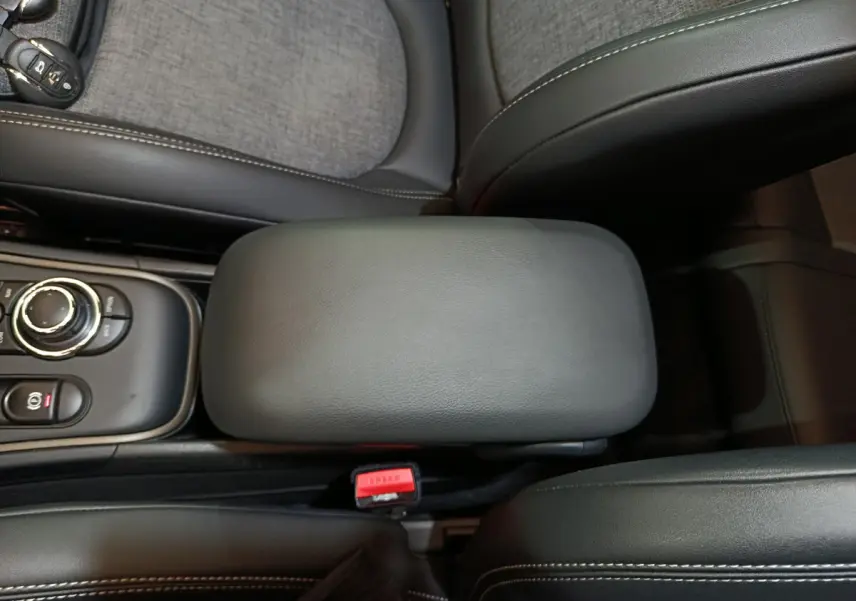 Vue rapprochée de l'accoudoir central noir et de la console avec molette du MINI Countryman blanc hybride rechargeable 2021.