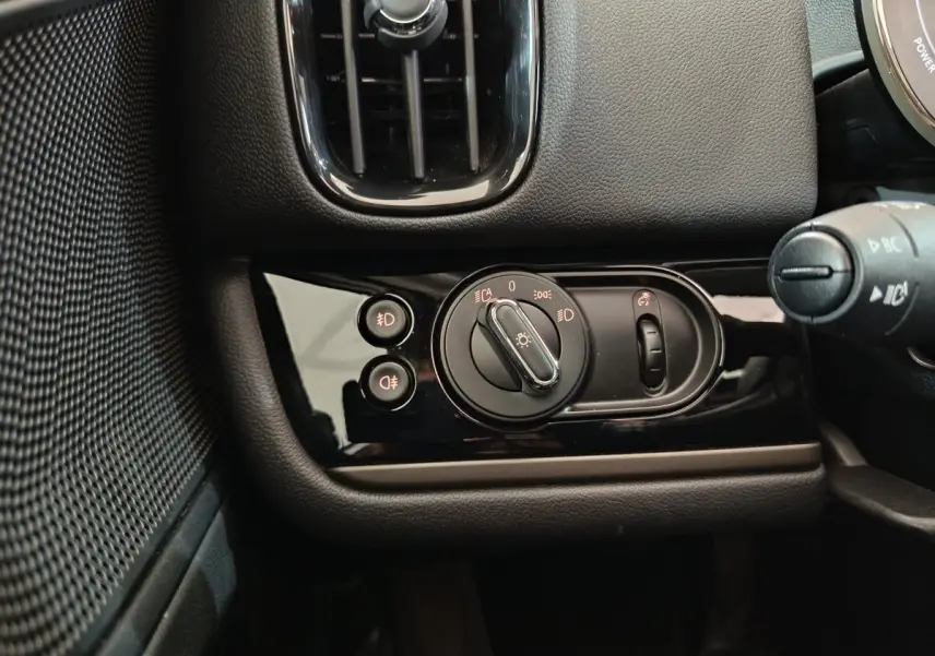 Détail du tableau de bord noir du MINI Countryman 2021 montrant les commandes d'éclairage et la ventilation côté gauche.