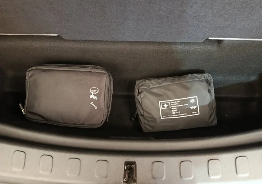 Vue plongeante sur le coffre avant noir d'un MINI Countryman blanc avec trousses de secours et outils rangées.