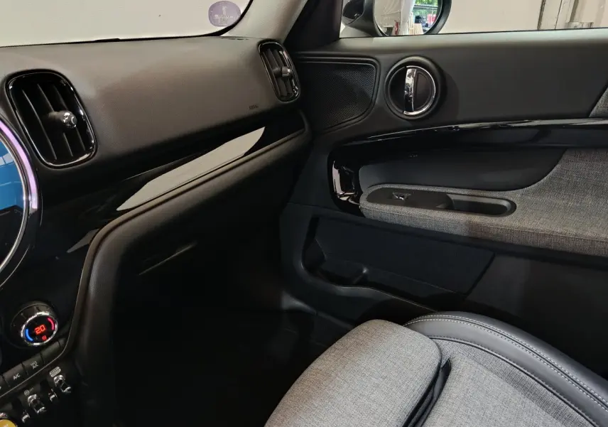 Intérieur côté passager du MINI Countryman blanc 2021, avec tableau de bord noir et garniture tissu gris.