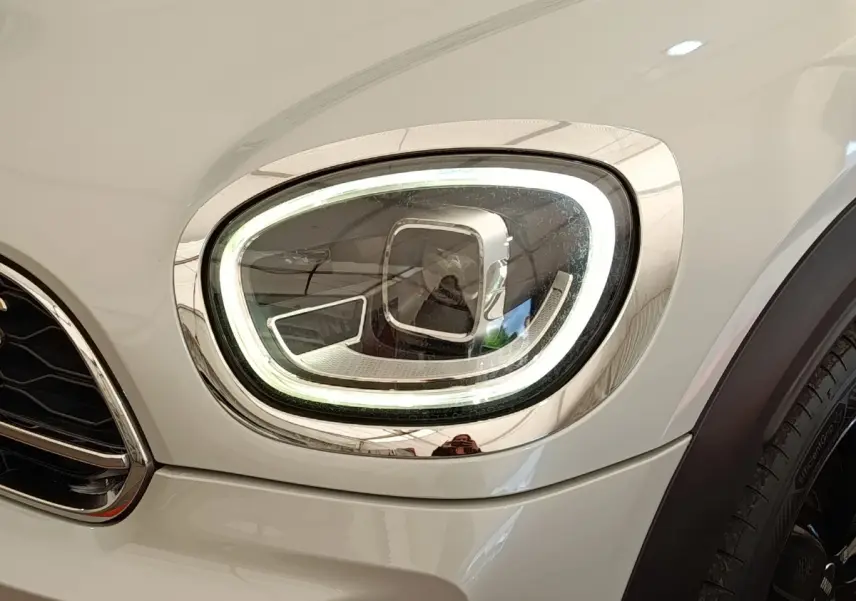 Gros plan sur le phare avant droit LED du MINI Countryman blanc, soulignant son contour lumineux distinctif.