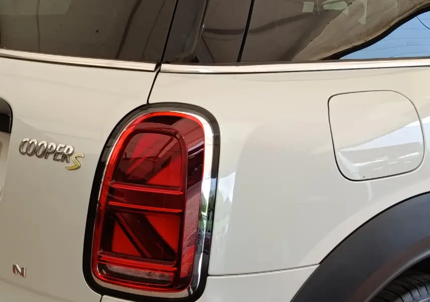 Gros plan sur le feu arrière gauche rouge et la trappe à carburant d'un MINI Countryman Cooper S blanc, vue arrière côté gauche.