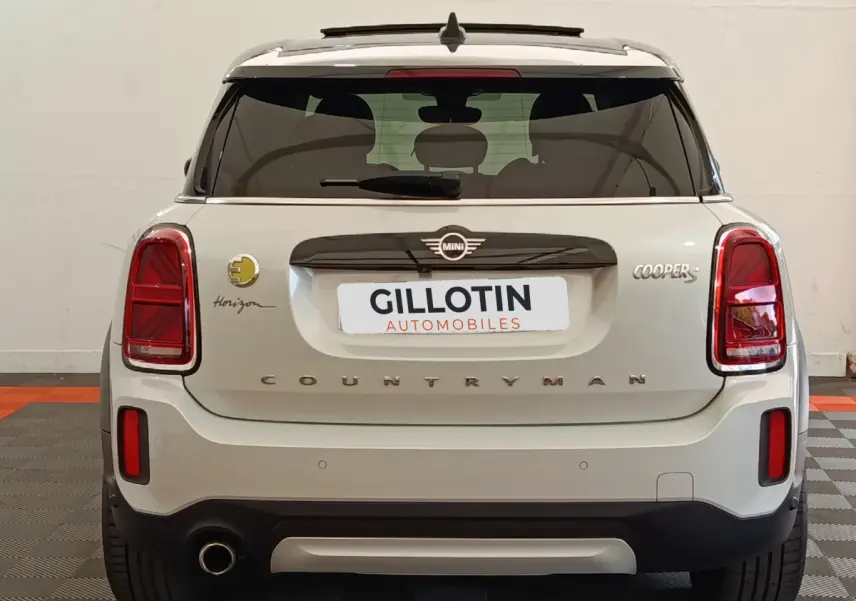 Vue arrière d'une MINI Countryman Cooper S blanche avec logo Horizon et feux arrière rouges dans un garage.