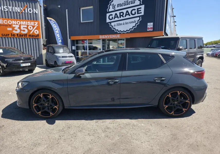 Vue de profil droit d'une CUPRA Leon 1.5 e-Hybrid bleu foncé avec jantes alliage 19'' cuivrées, vitres arrière surteintées.