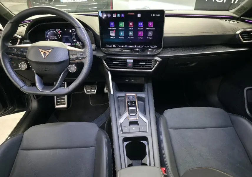 Vue intérieure avant de la CUPRA Leon 2024, volant cuir noir avec logo cuivré et écran tactile central HD.