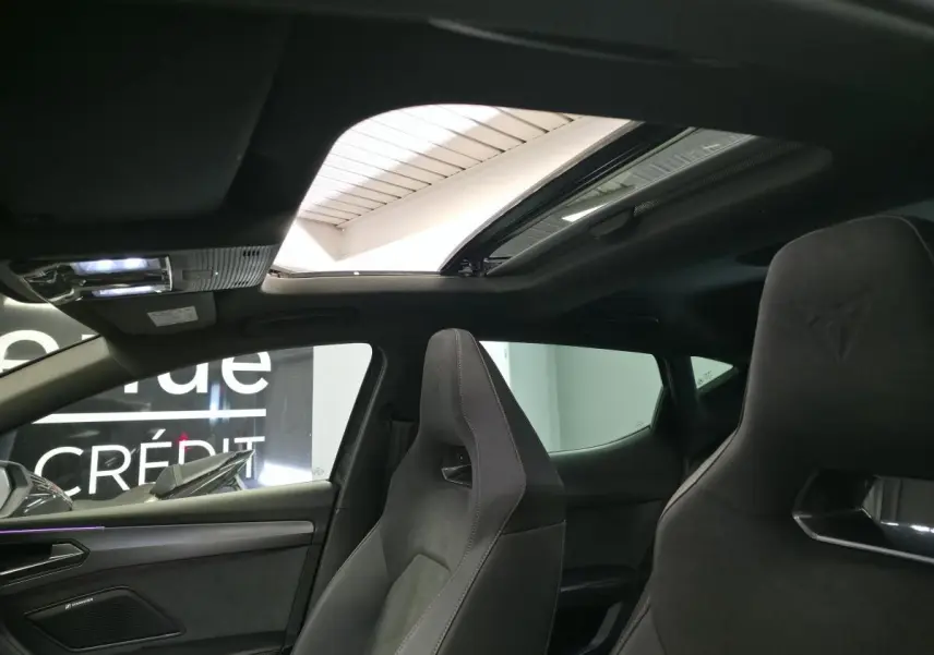 Intérieur de la CUPRA Leon 2024 vu côté droit, sièges baquets noirs avec logo embossé et toit ouvrant panoramique.