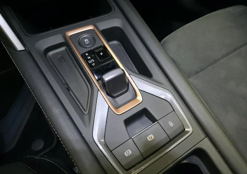 Gros plan sur la console centrale avec levier de vitesse et cadre cuivré dans l’habitacle noir du CUPRA Leon 2024.