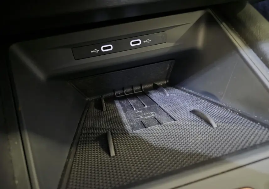 Gros plan sur la zone de recharge avec deux ports USB-C éclairés dans l’habitacle noir du CUPRA Leon bleu 2024.