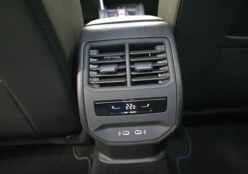 Détail de la console arrière noire avec aérateurs, affichage digital de la climatisation à 22°C et deux prises USB-C.