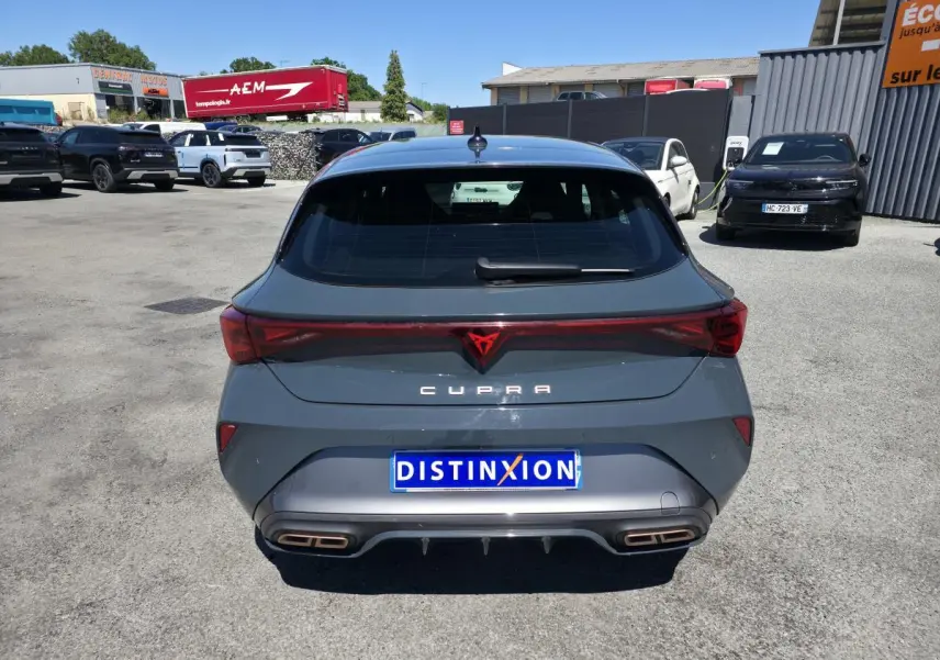 Vue arrière d'une CUPRA Leon 2024 gris foncé avec feux arrière reliés et double sortie d'échappement cuivrée.