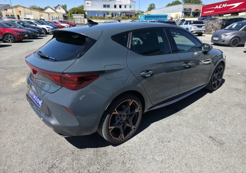 Vue 3/4 arrière droite d'une CUPRA Leon 1.5 e-Hybrid 2024 bleu Fjord avec jantes alliage 19'' polar cuivrées et toit noir.