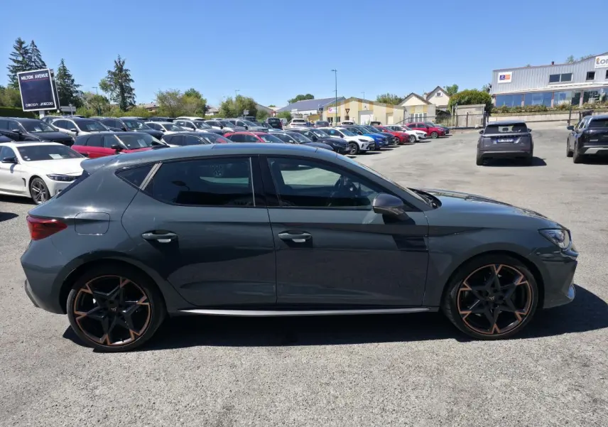 Profil droit d'une CUPRA Leon 1.5 e-Hybrid 2024 bleu foncé avec jantes alliage 19'' cuivrées et vitres surteintées.