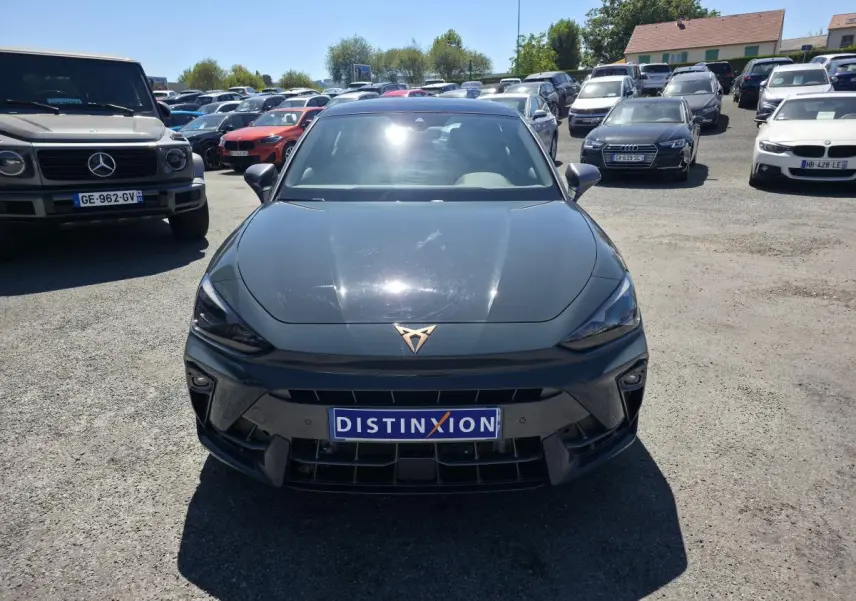 Vue avant d’une CUPRA Leon 1.5 e-Hybrid bleu avec logo cuivré et plaque Distinxion sur un parking.