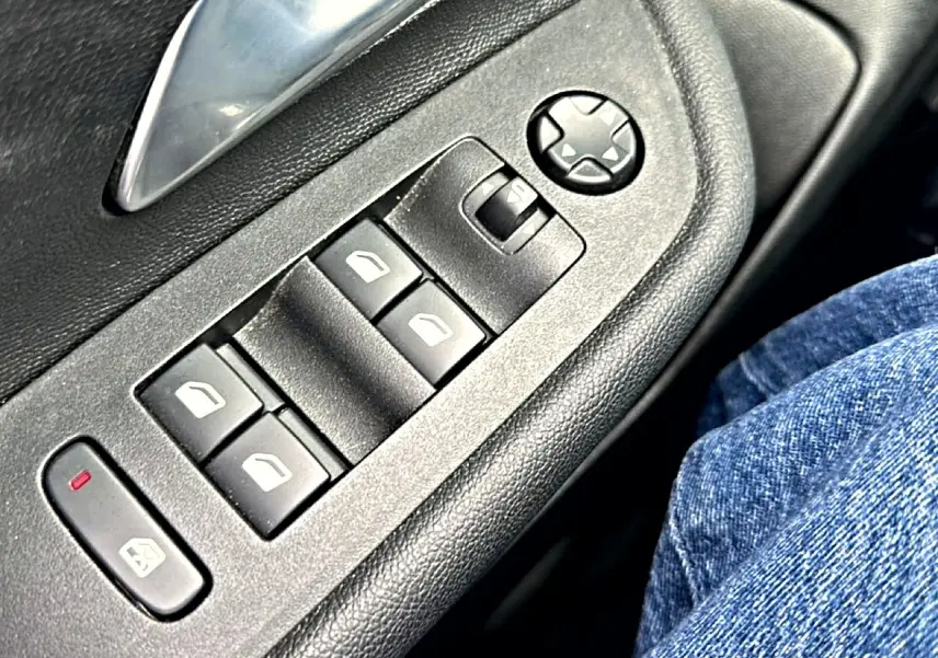 Gros plan sur les commandes de lève-vitres et rétroviseurs côté conducteur de l'Opel Mokka gris 2025.