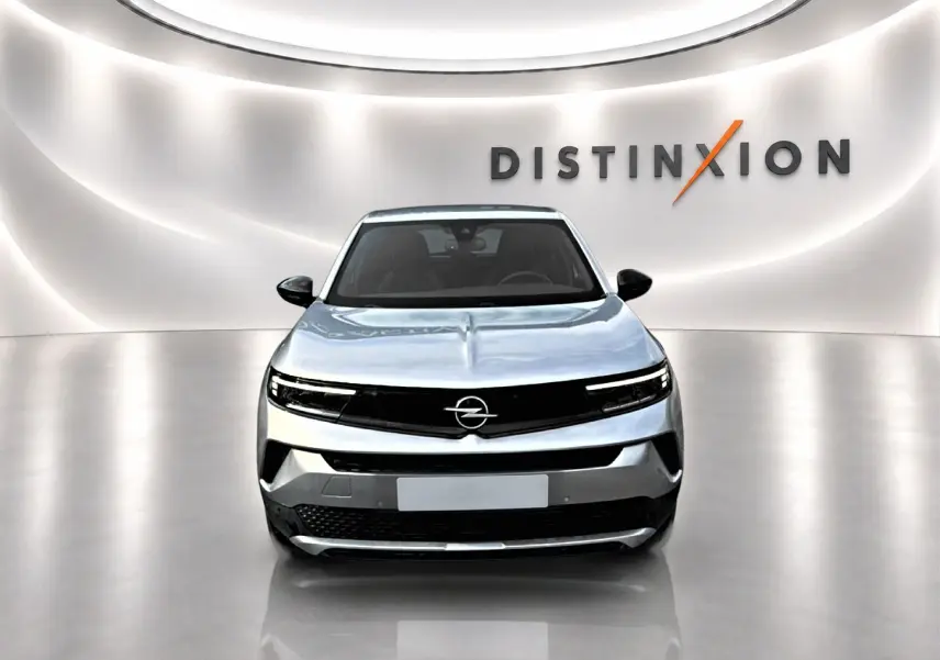 Vue frontale de l'Opel Mokka gris 2025 avec calandre noire et éclairage LED fin dans un showroom lumineux.