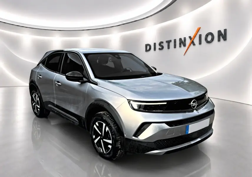 Opel Mokka gris en 3/4 avant droit, avec calandre noire et jantes au design moderne, dans un showroom lumineux.