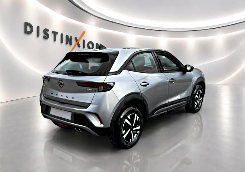 Vue 3/4 arrière droite d'un Opel Mokka gris 2025 avec feux arrière LED et jantes bicolores en studio lumineux.