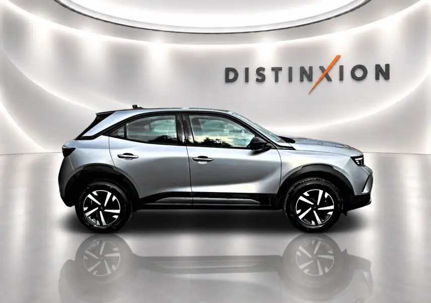 Opel Mokka gris en profil droit dans un studio lumineux avec jantes noires et blanches distinctives.