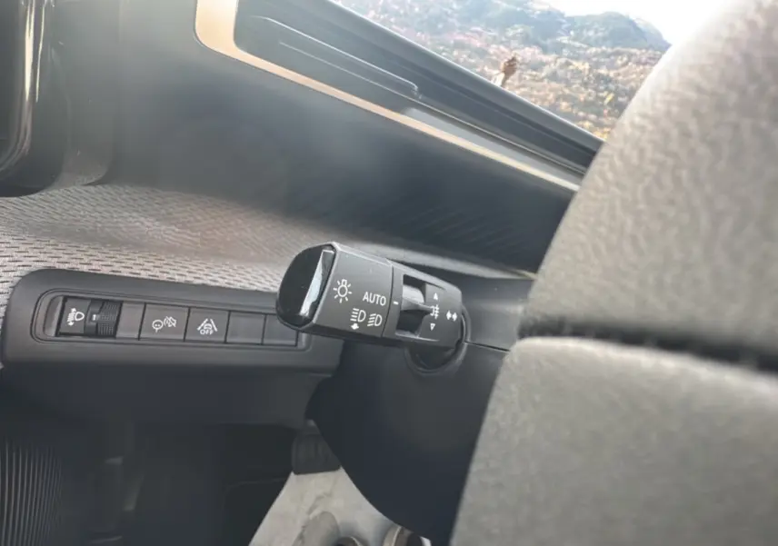 Gros plan sur la commande des feux automatique et des aides à la conduite dans l'habitacle d'une Citroën C3 Aircross gris mercury.