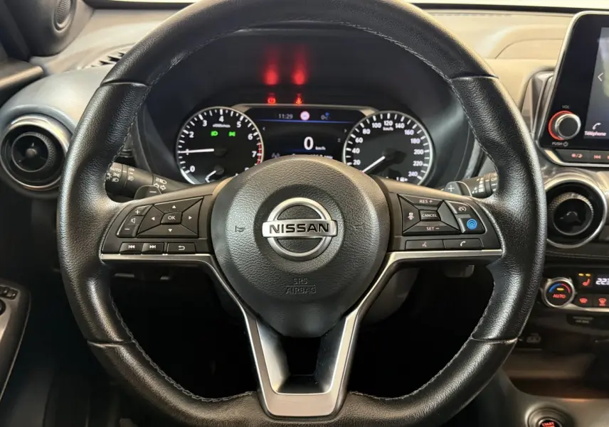 Vue rapprochée du volant cuir noir du Nissan Juke 2021 avec commandes multifonctions et tableau de bord digital.