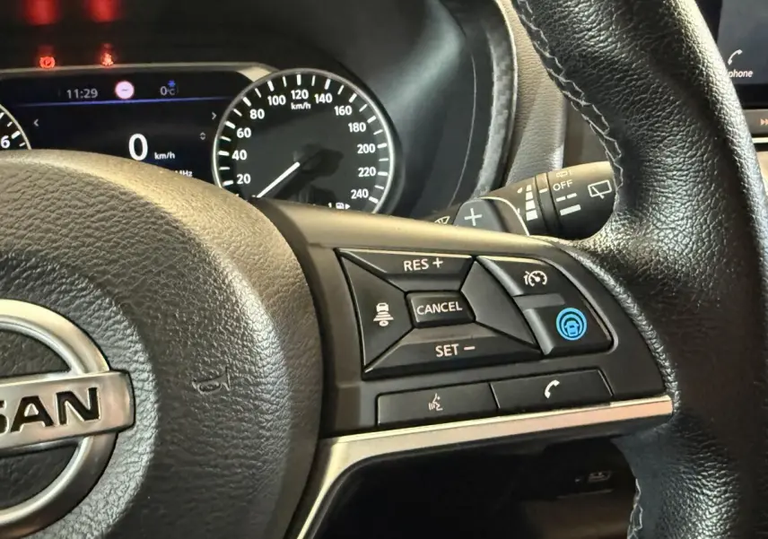 Gros plan sur le volant cuir noir du Nissan Juke 2021 avec commandes de régulateur et tableau de bord digital.