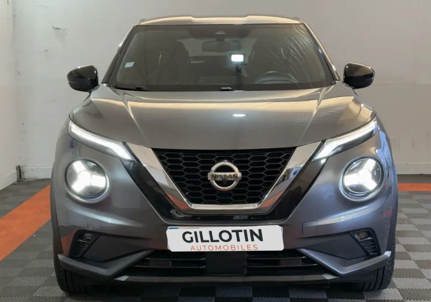 Vue frontale d'un Nissan Juke gris clair 2021 avec phares LED allumés dans un garage.