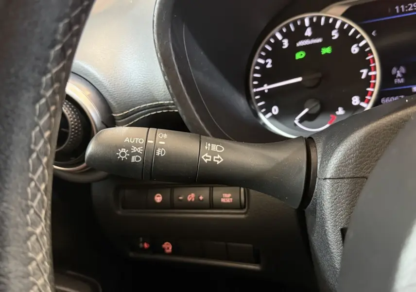 Gros plan sur la manette de phares et clignotants à gauche du volant dans le tableau de bord noir du Nissan Juke gris clair 2021.