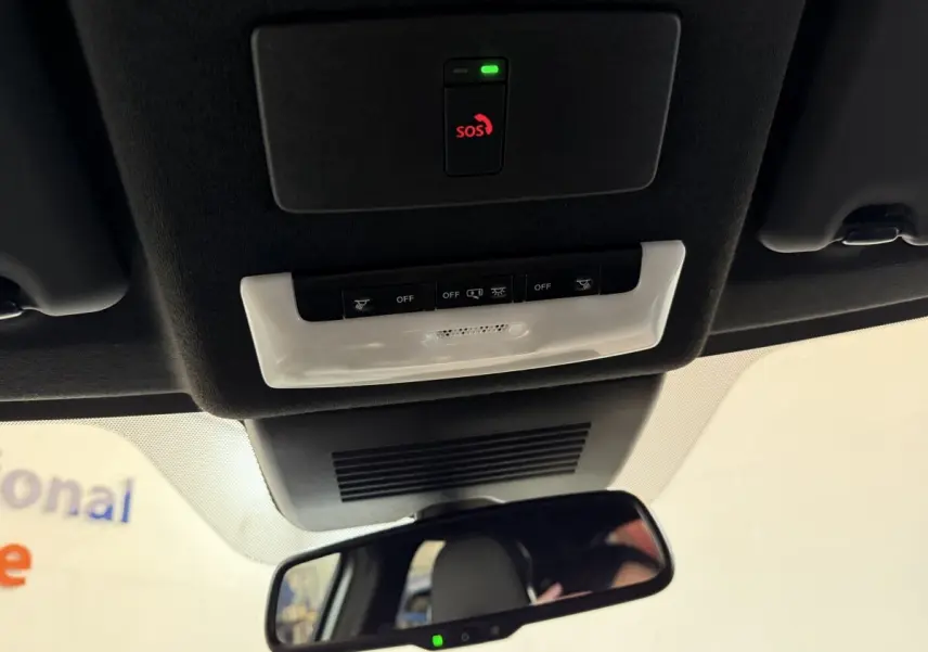 Vue intérieure du plafond avec commandes d'éclairage, bouton SOS et rétroviseur dans un Nissan Juke gris clair 2021.