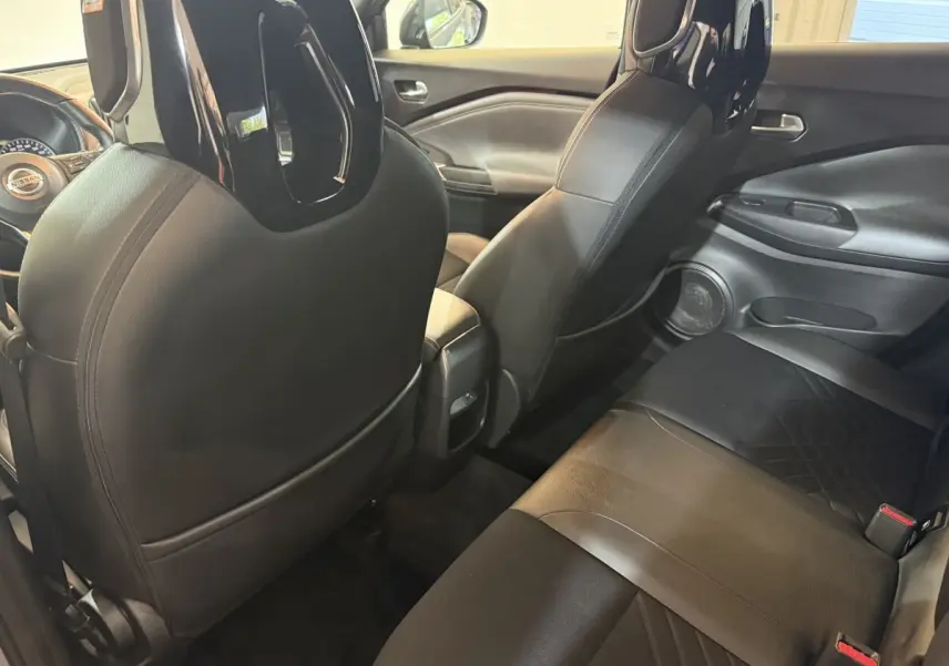 Vue intérieure arrière côté droit du Nissan Juke gris clair 2021, sièges en cuir noir avec appuie-tête Bose.