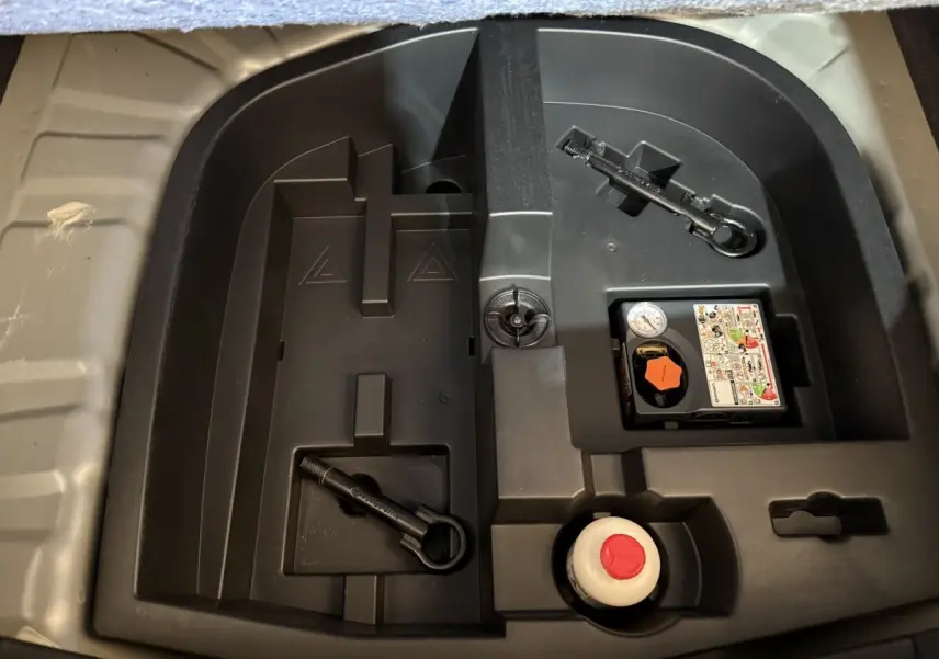 Compartiment de rangement sous le coffre du Nissan Juke gris clair 2021 avec kit de réparation pneus et outils.