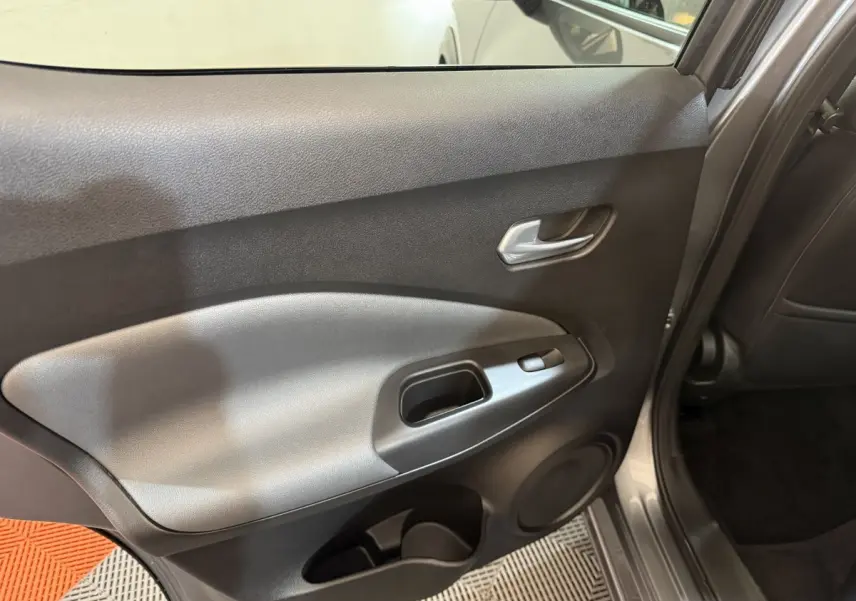 Vue intérieure côté gauche de la porte arrière gris clair du Nissan Juke 2021 avec poignée et commande de fenêtre.