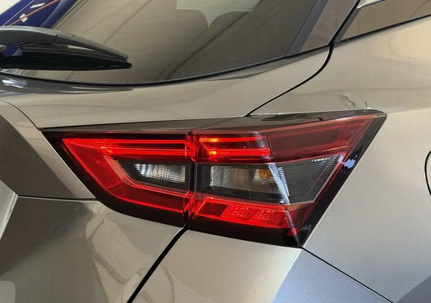 Gros plan sur le feu arrière droit rouge du Nissan Juke gris clair, soulignant les lignes anguleuses du coffre.