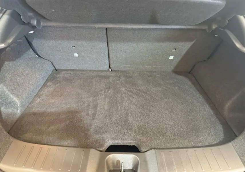 Coffre ouvert du Nissan Juke gris clair 2021, vue intérieure montrant le plancher et la banquette arrière rabattue.