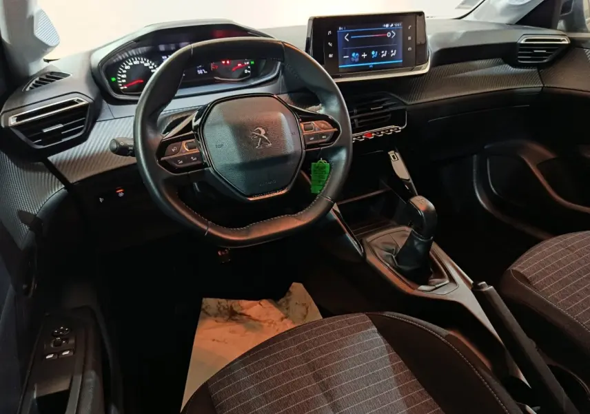 Vue intérieure avant de la Peugeot 208 1.2 PT 75 S&S Premium 2022, volant compact, écran tactile et levier de vitesses manuel.
