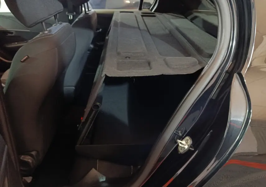 Vue intérieure côté droit du coffre ouvert avec banquette arrière rabattue d'une Peugeot 208 noire 2022.