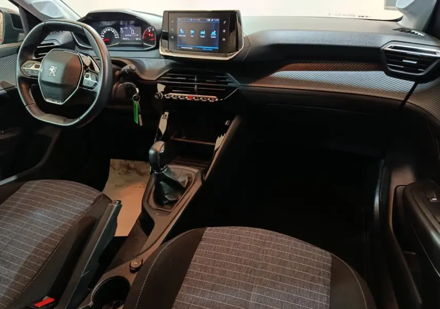 Intérieur Peugeot 208 2022 vu côté conducteur, tableau de bord avec écran tactile et volant compact noir.