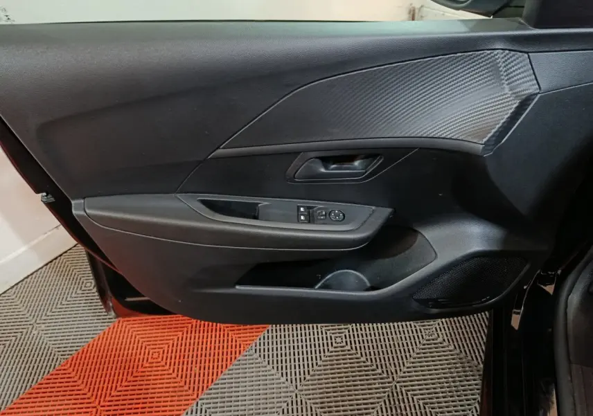 Vue rapprochée de la porte avant gauche noire d’une Peugeot 208 2022 avec commandes de vitres et miroir.
