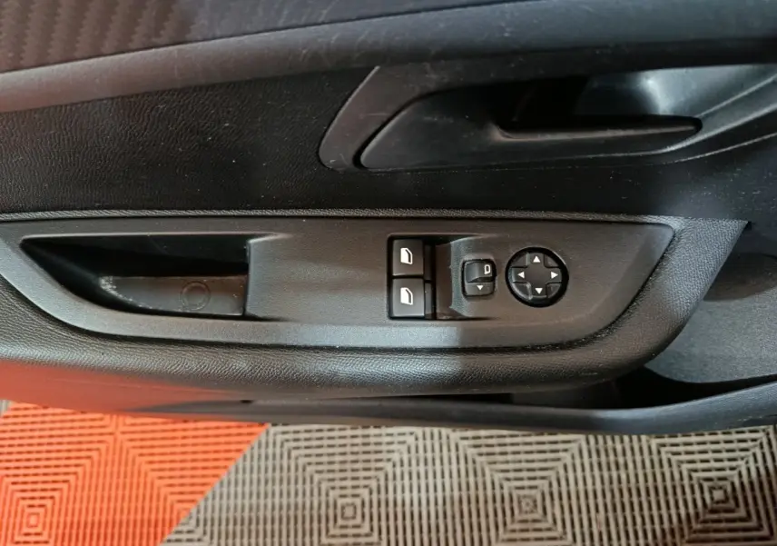 Vue rapprochée des commandes de réglage des rétroviseurs et des vitres côté conducteur d'une Peugeot 208 noire 2022.