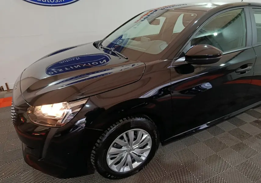 Vue 3/4 avant droit d'une Peugeot 208 noire 2022 avec phares allumés et jantes alliage visibles.