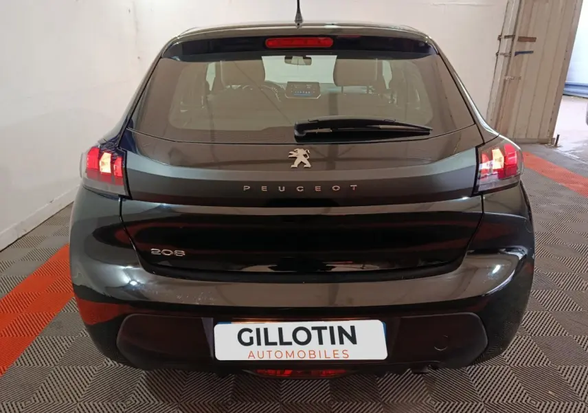 Vue arrière d'une Peugeot 208 noire 2022 avec feux LED allumés dans un garage intérieur.