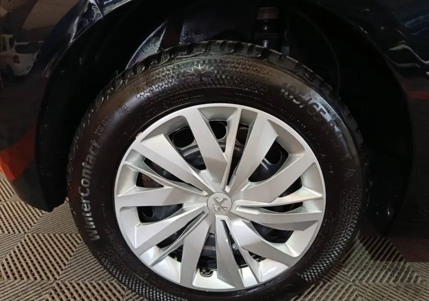 Gros plan sur la roue avant droite d'une Peugeot 208 noire de 2022 avec jante argentée et pneu hiver WinterContact.