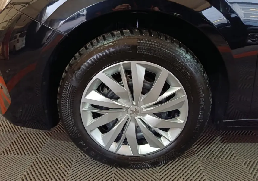 Gros plan sur la roue avant droite d'une Peugeot 208 noire, mettant en valeur la jante argentée et le pneu Continental.