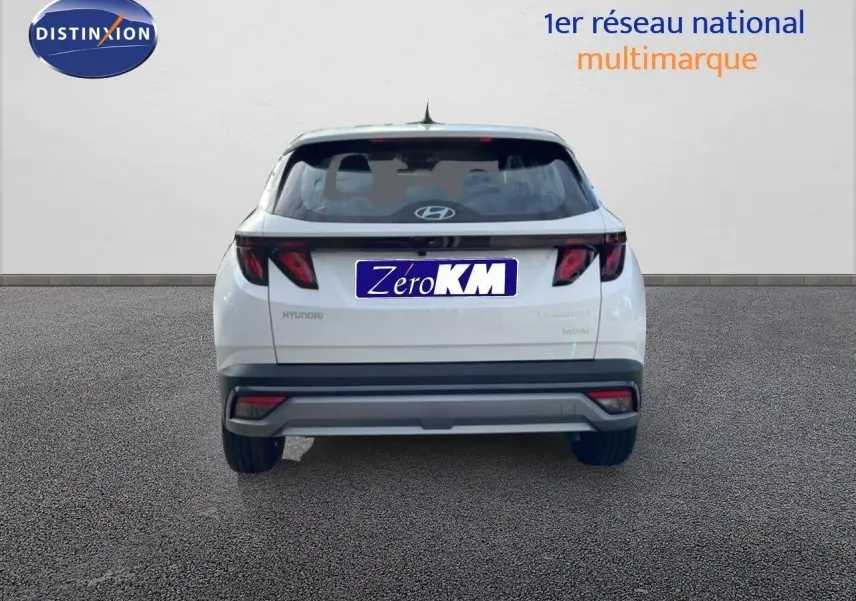 Vue arrière d'un Hyundai Tucson blanc Atlas 2026 avec feux arrière sombres et logo Hyundai visible.