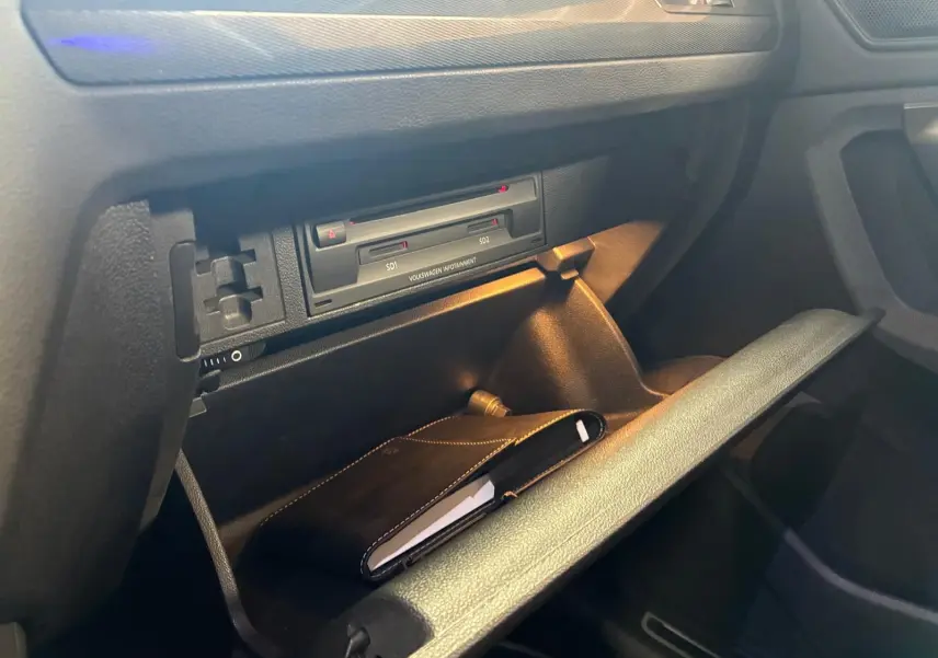 Gros plan sur la boîte à gants ouverte du Volkswagen Tiguan gris 2020, avec un carnet noir à l'intérieur.