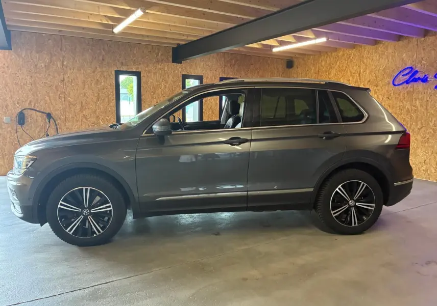 Vue de profil côté gauche d'un Volkswagen Tiguan gris 2020, avec jantes noires et intérieur visible à travers les vitres.