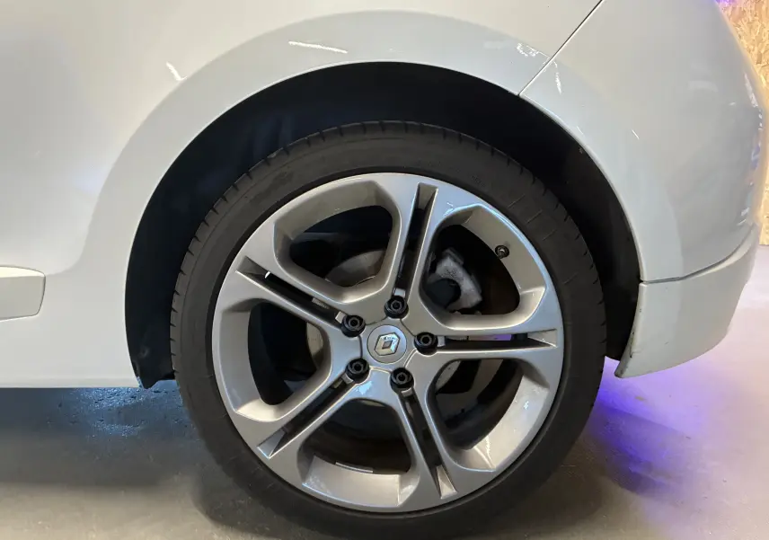 Gros plan sur la roue arrière droite blanche d'une Renault Mégane Coupé 2.0 DCI 165 GT avec jante alliage distinctive.