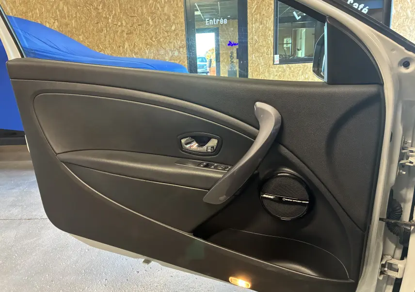 Vue intérieure côté gauche de la porte avant blanche d'une Renault Mégane Coupé 2.0 DCI avec haut-parleur Bose intégré.